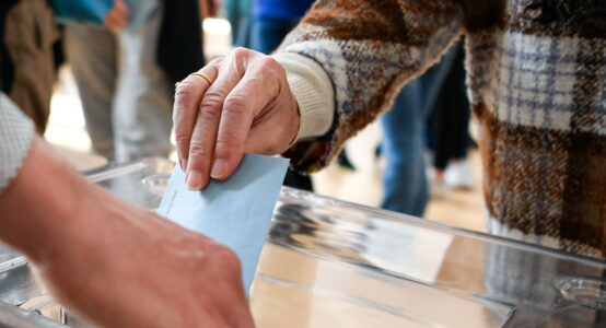 A person putting a ballot paper into a box.