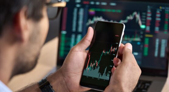 A man looking at a graph showing stock market performance on his phone.