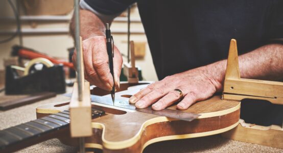 A man fixing a guitar in a workshop.