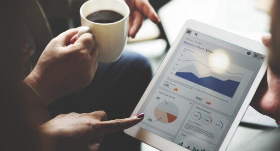 A group of people reviewing performance on a tablet.