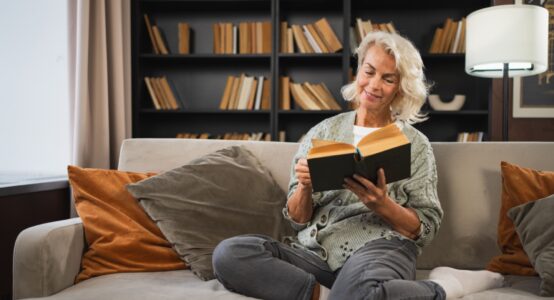 Smiling lady sitting on a sofa reading a book