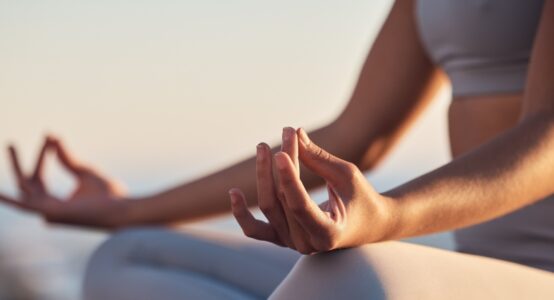 A woman sitting in the lotus position mediating.