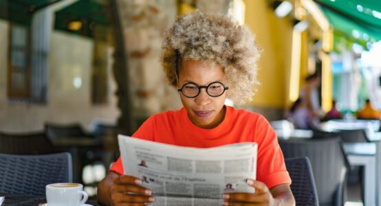 A woman reading a newspaper in a café.