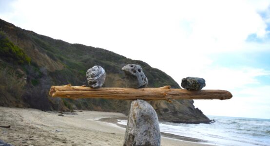 Rocks balancing on log on top of another rock